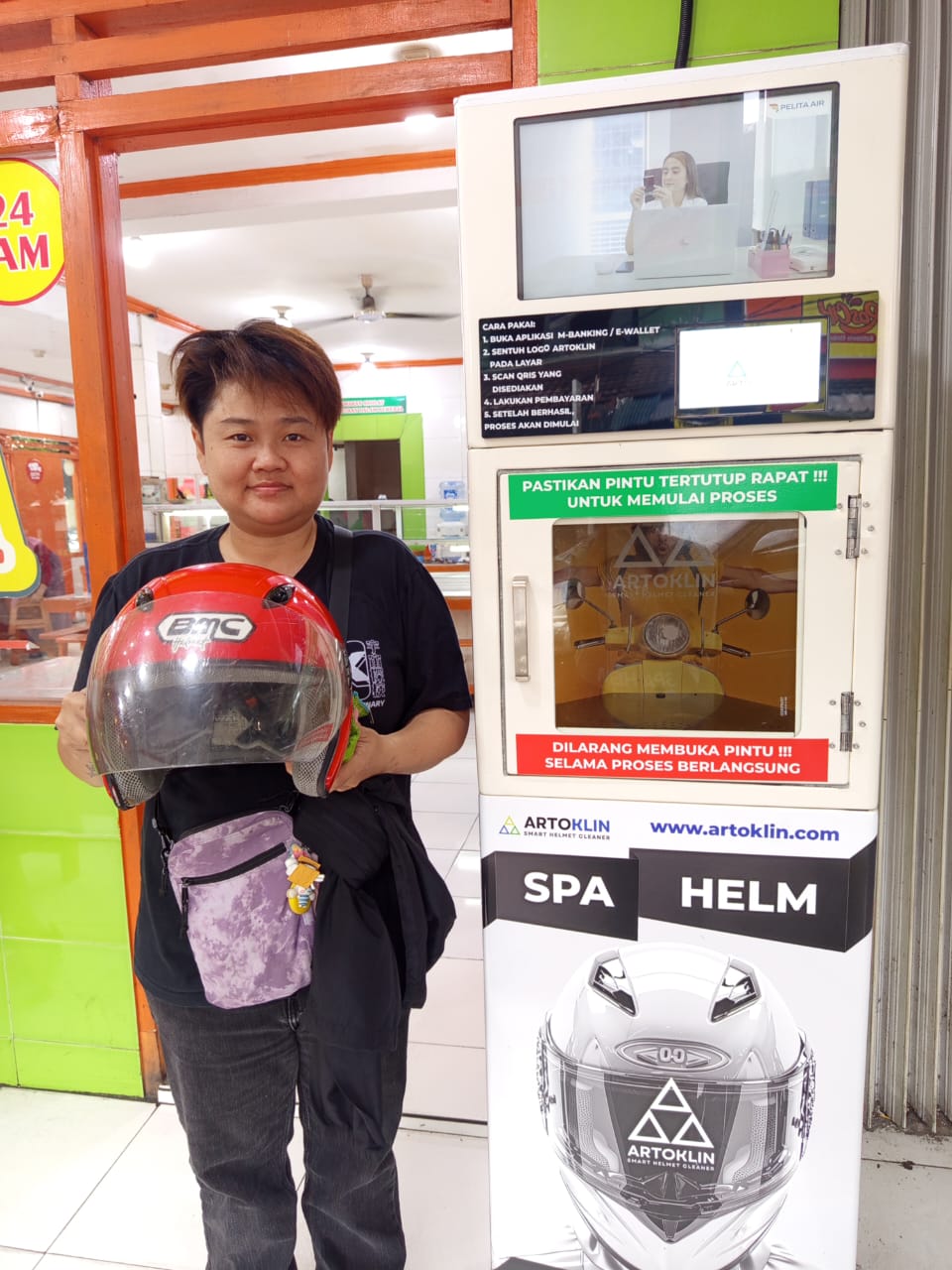 Customer holding a red helmet at an Artoklin location